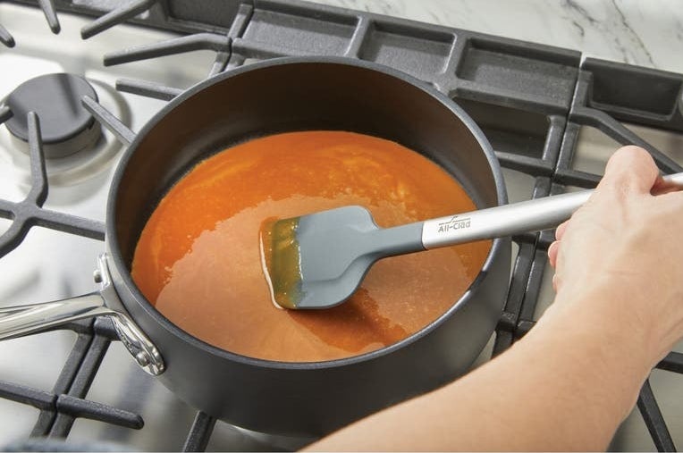 Model using spatula on soup