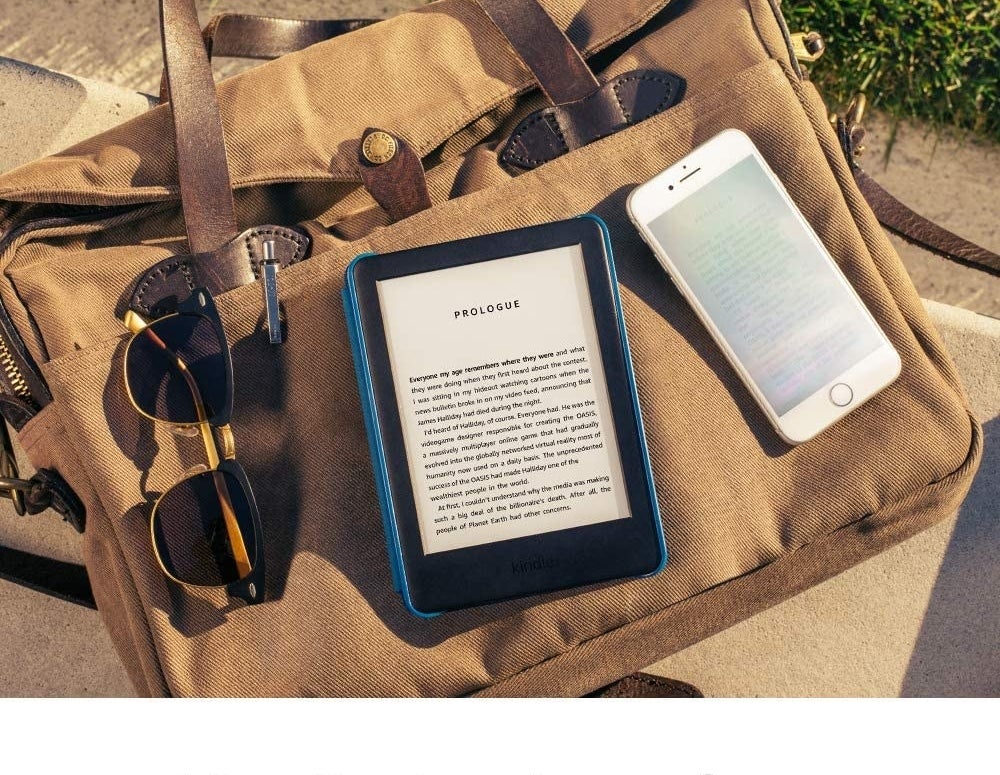 kindle styled on top of a beach bag with sunglasses and cell phone
