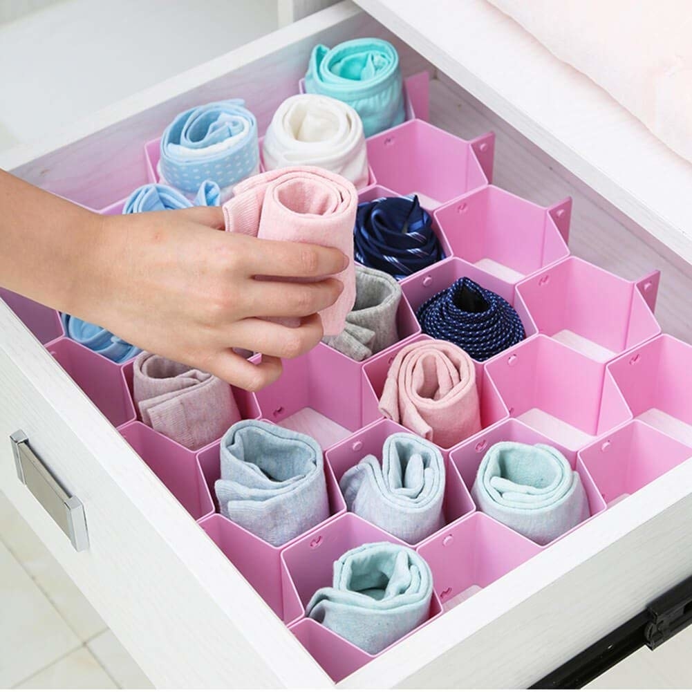 A pink honeycomb-shaped drawer organiser with blue and pink towels folded into it 