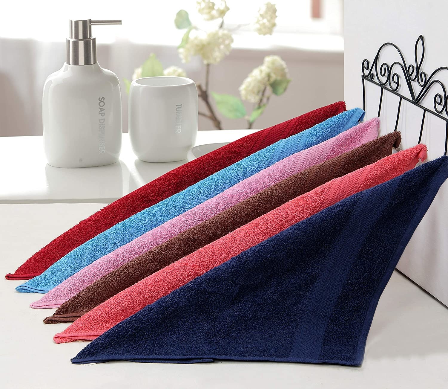 A set of multi-coloured towels arranged on a bathroom stand. 