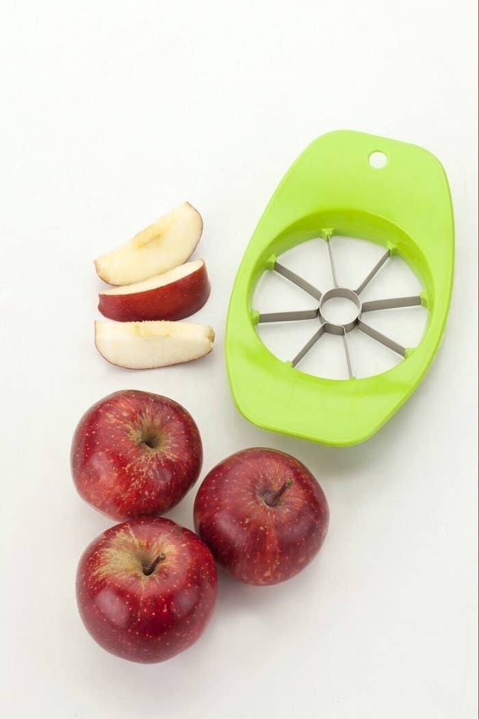 An apple cutter with 3 apples and apple slices 