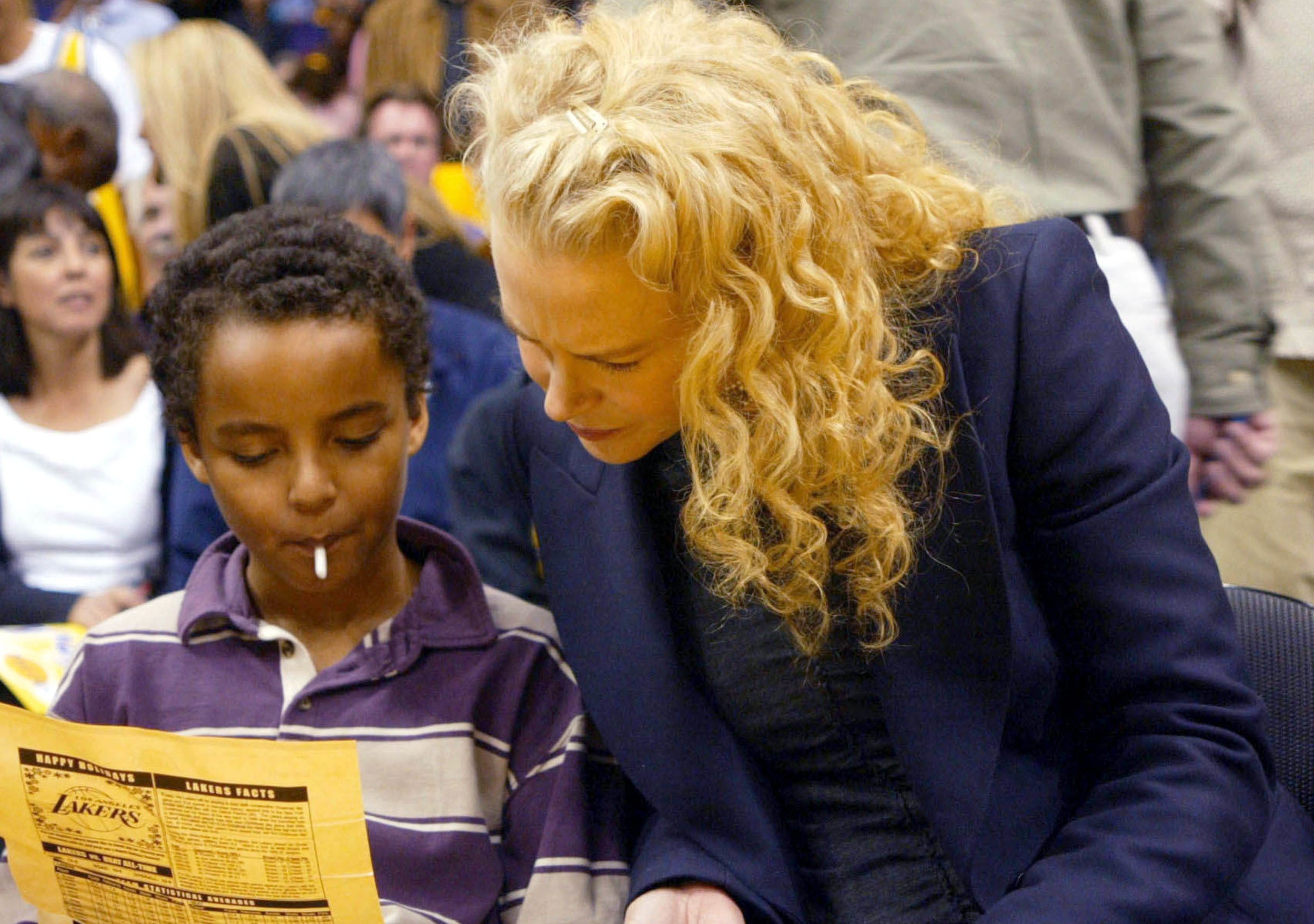 Nicole reads a piece of paper with a young Connor at a basketball game