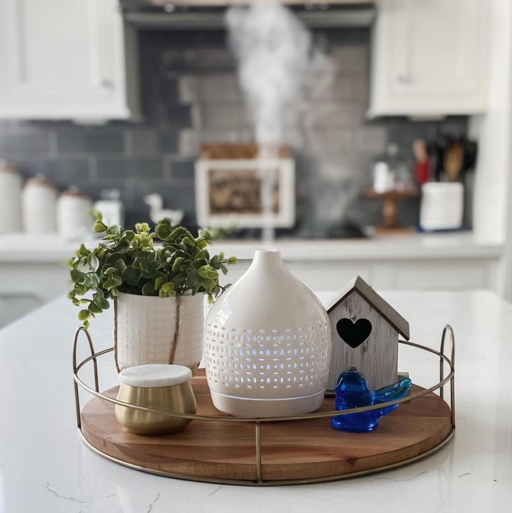 the oil diffuser on a countertop serving tray with other decor 