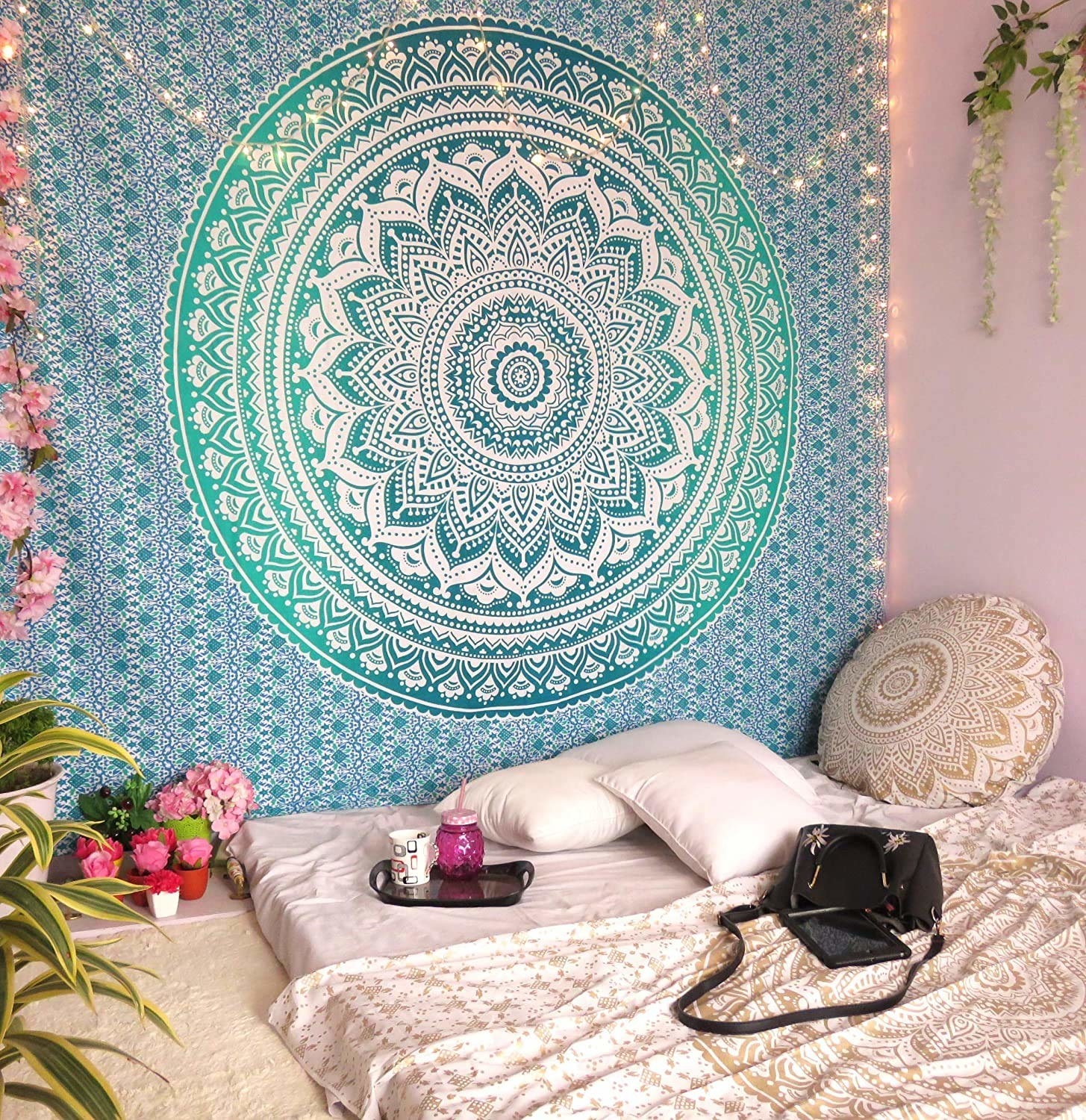 A white, blue an d green Mandala tapestry on a wall, up against a mattress.