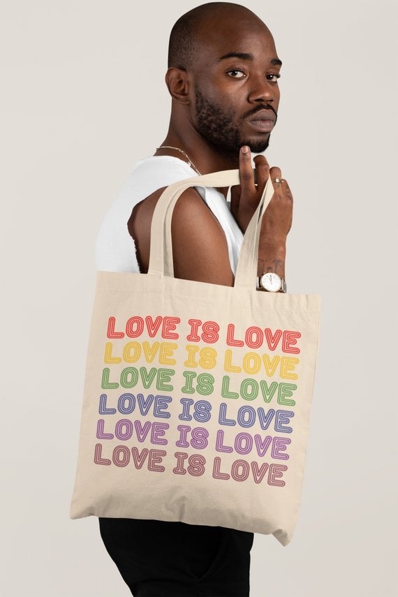 square tote bag with rainbow letters that say &quot;love is love&quot; 