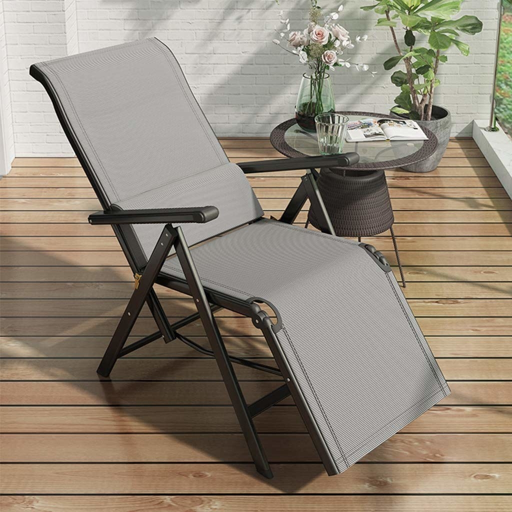 A black and grey PROSFIA Folding Lounge Chair on an outside deck.