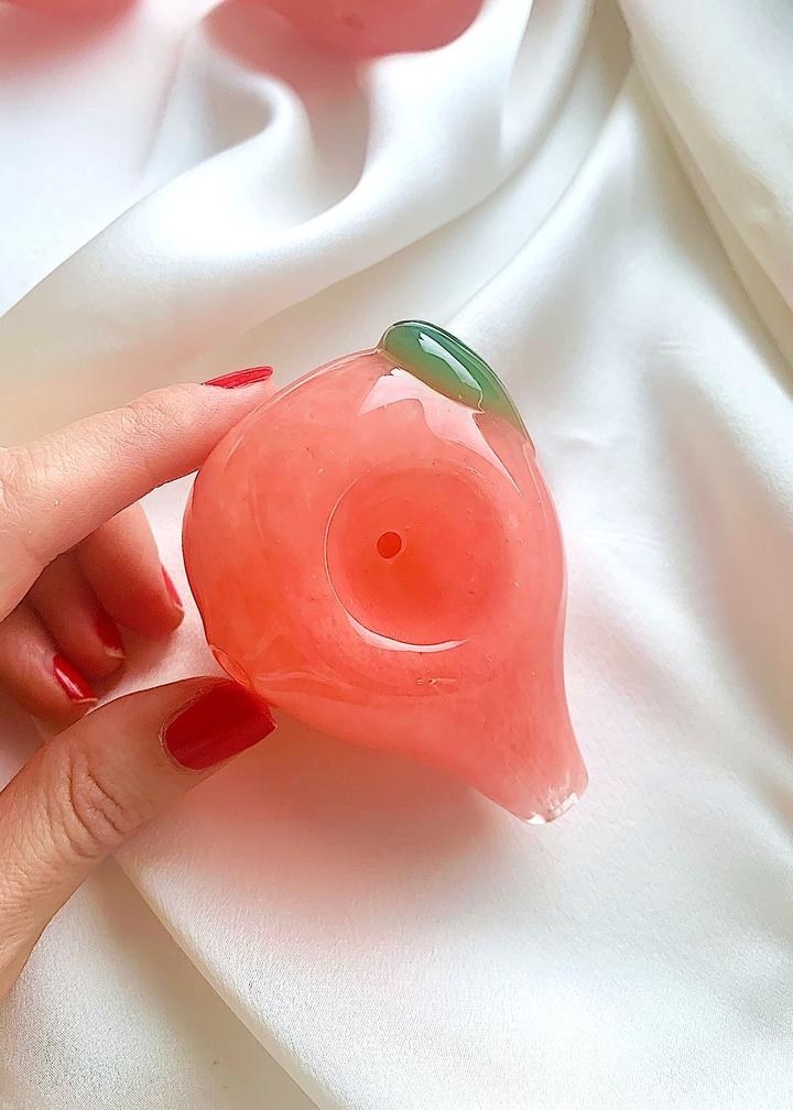 someone holding the peach pink peach pipe to show how small it is