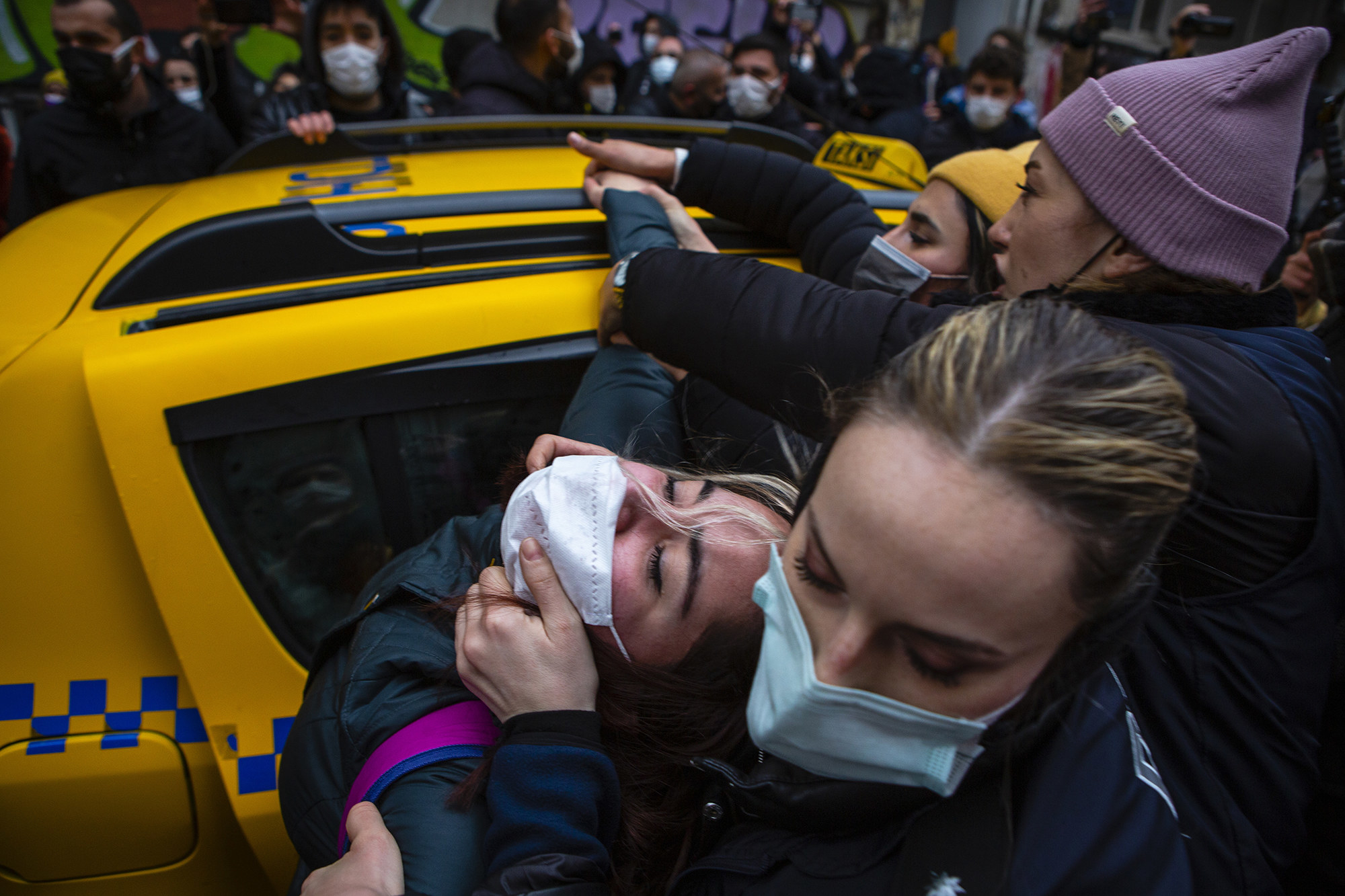 A protester is being pulled from a cab by their face