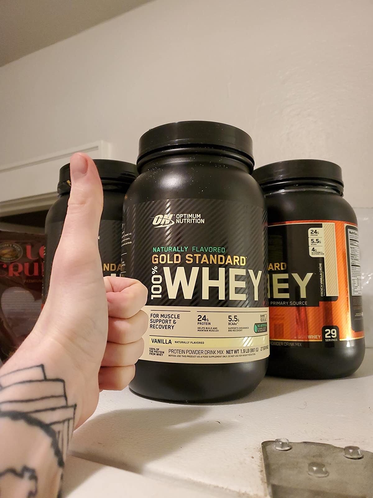 image of reviewer giving a thumbs up to a container of vanilla gold standard protein powder