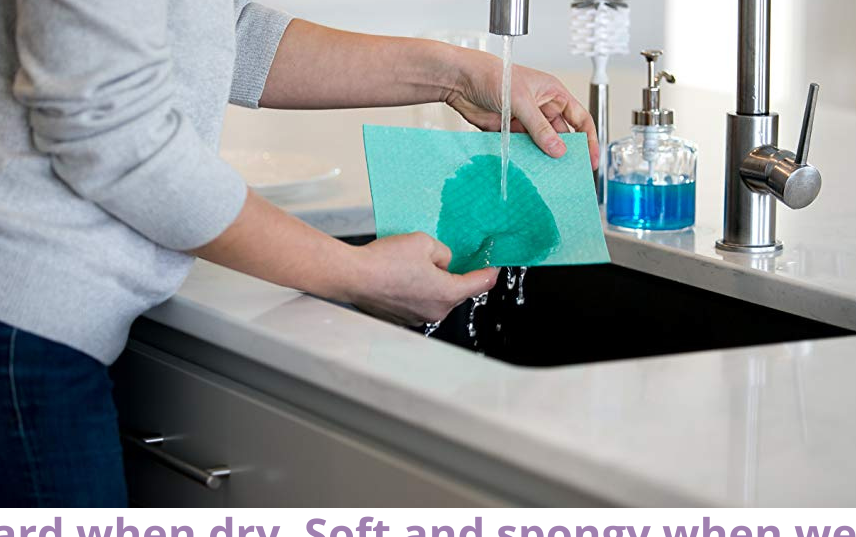 model running a green swedish dishcloth under the kitchen sink