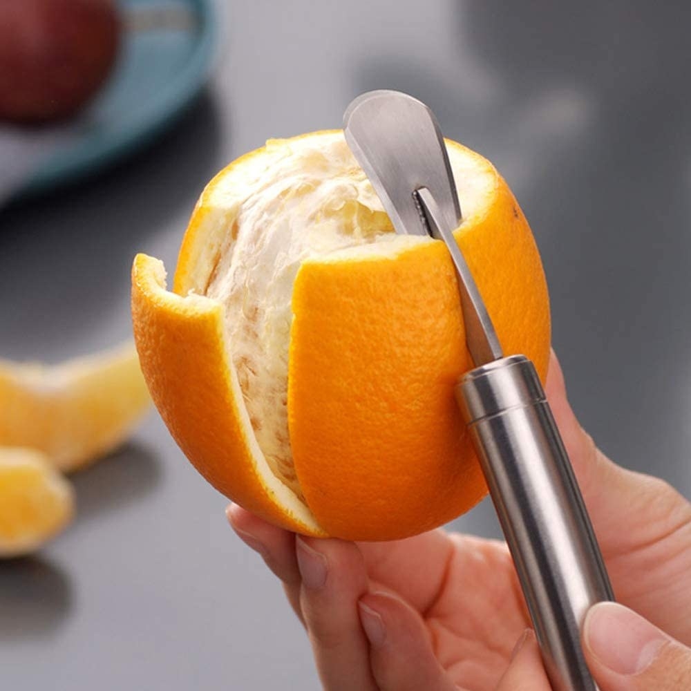 Someone using the peeler to peel an orange