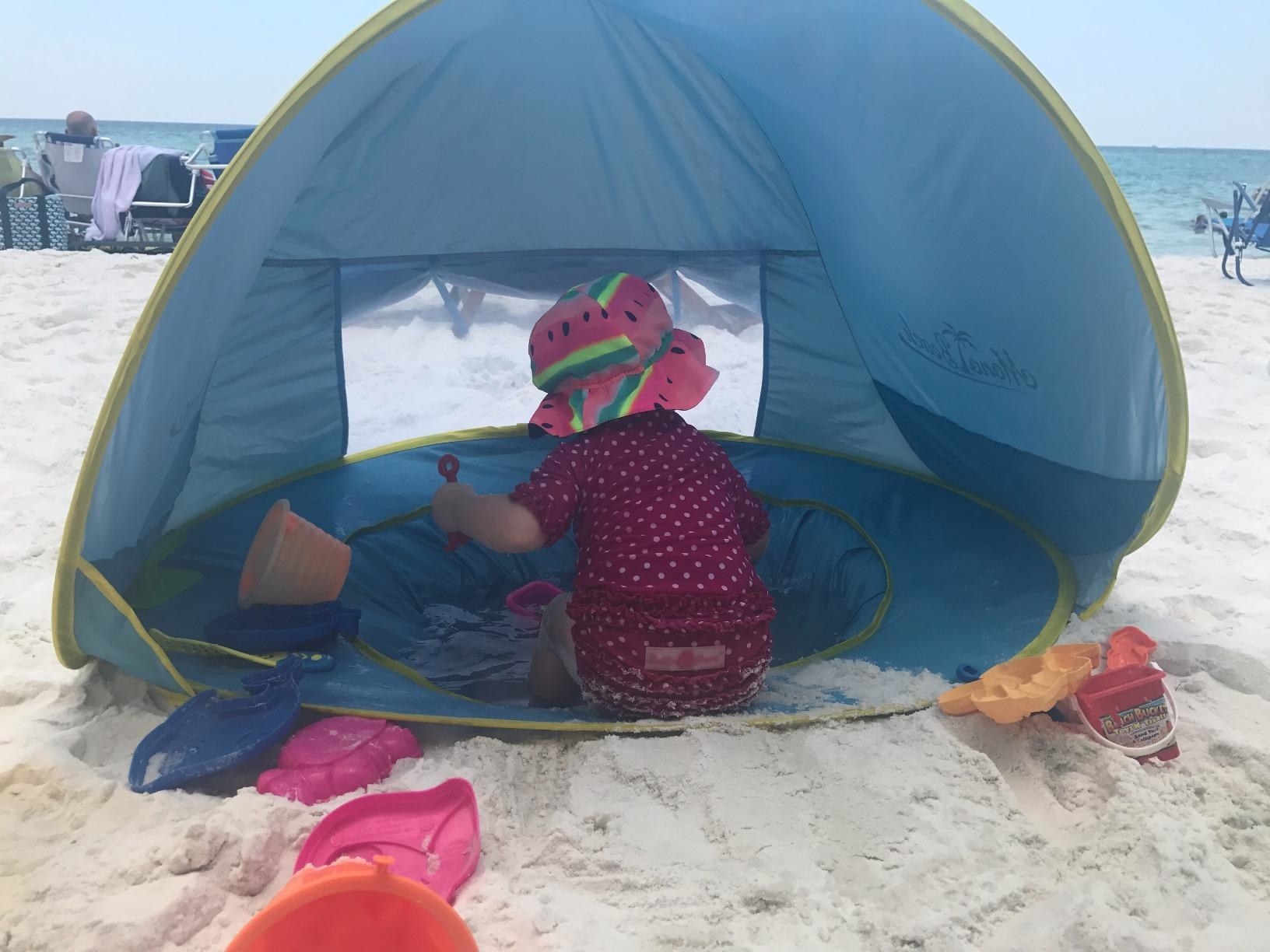 A baby playing in the tent wading pool on the beach