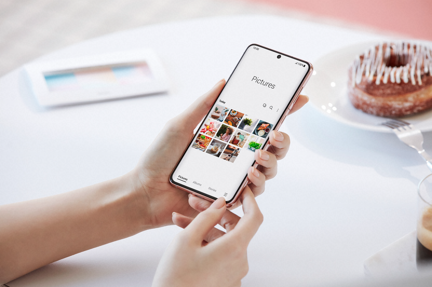 A pair of hands holding a phone at a table.