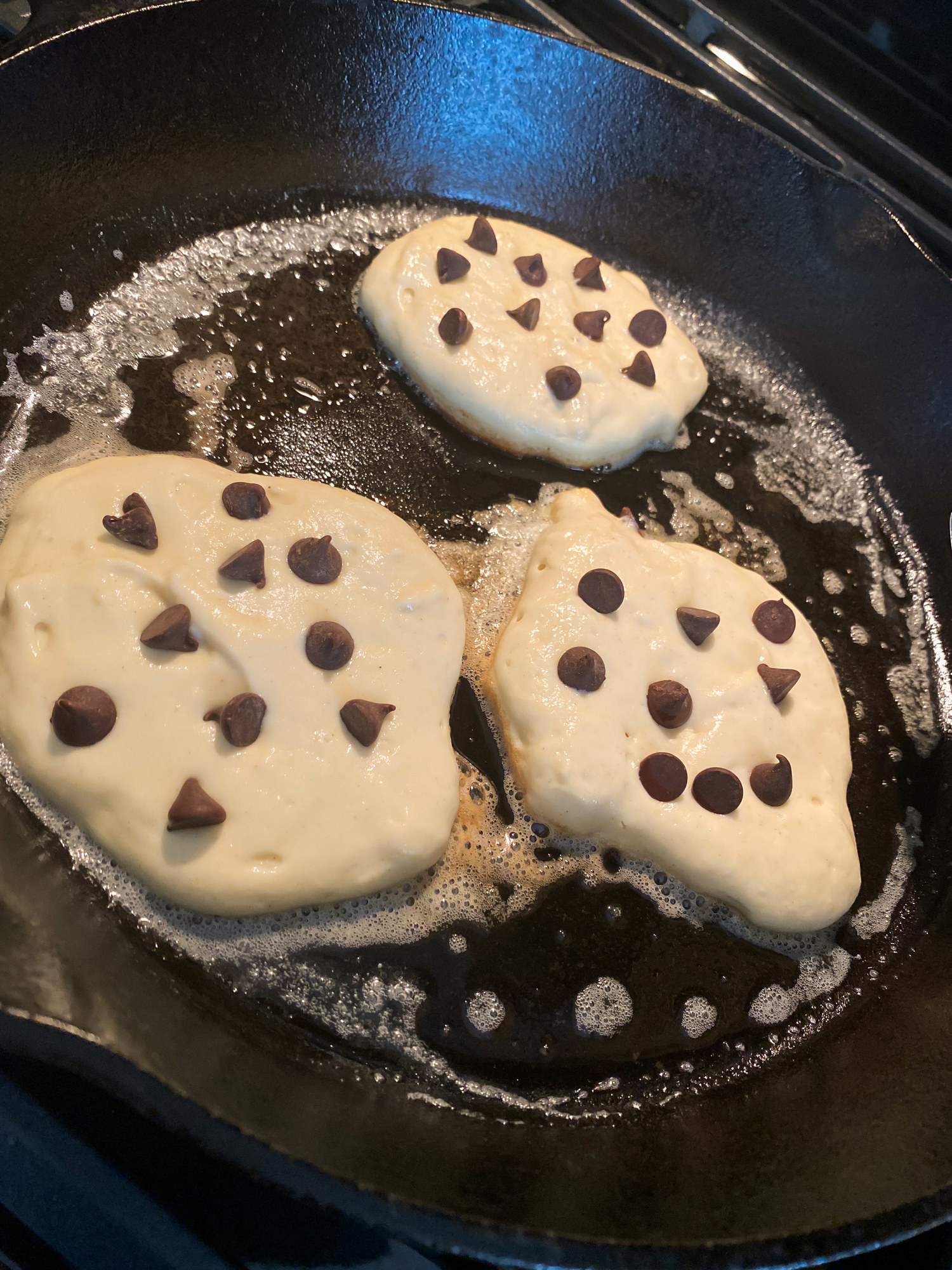 Chocolate chip pancakes cooking in a cast iron skillet