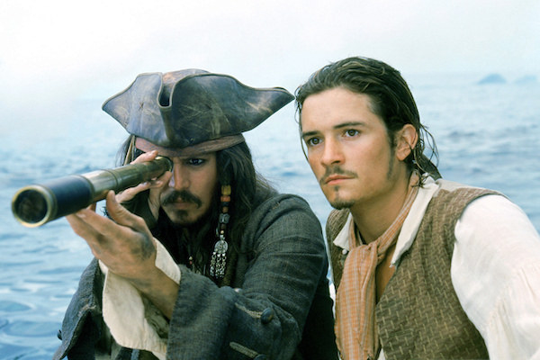 Johnny Depp looking through a spyglass while Orlando Bloom stares ahead