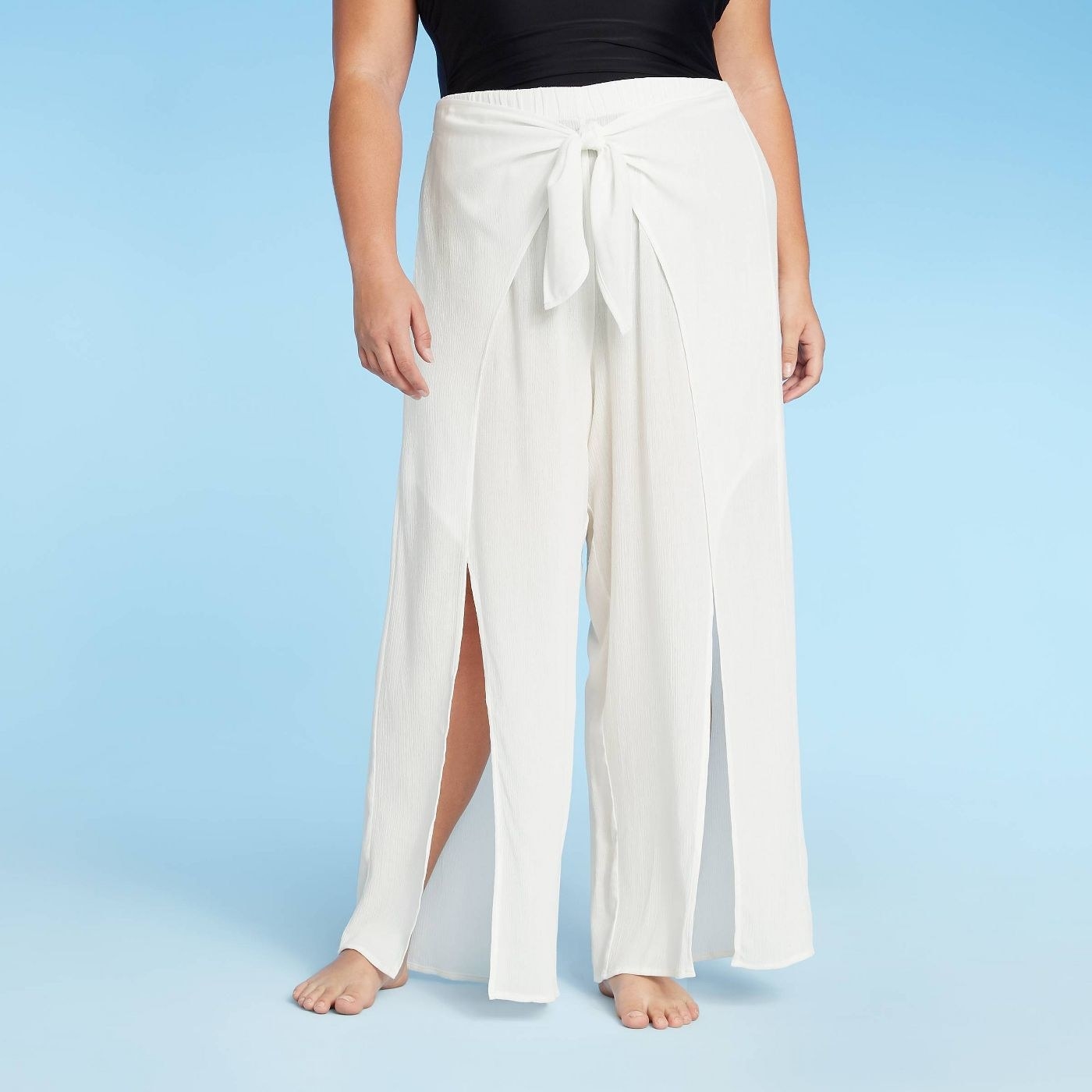 Model wearing white cover up with slits that stop above the knee