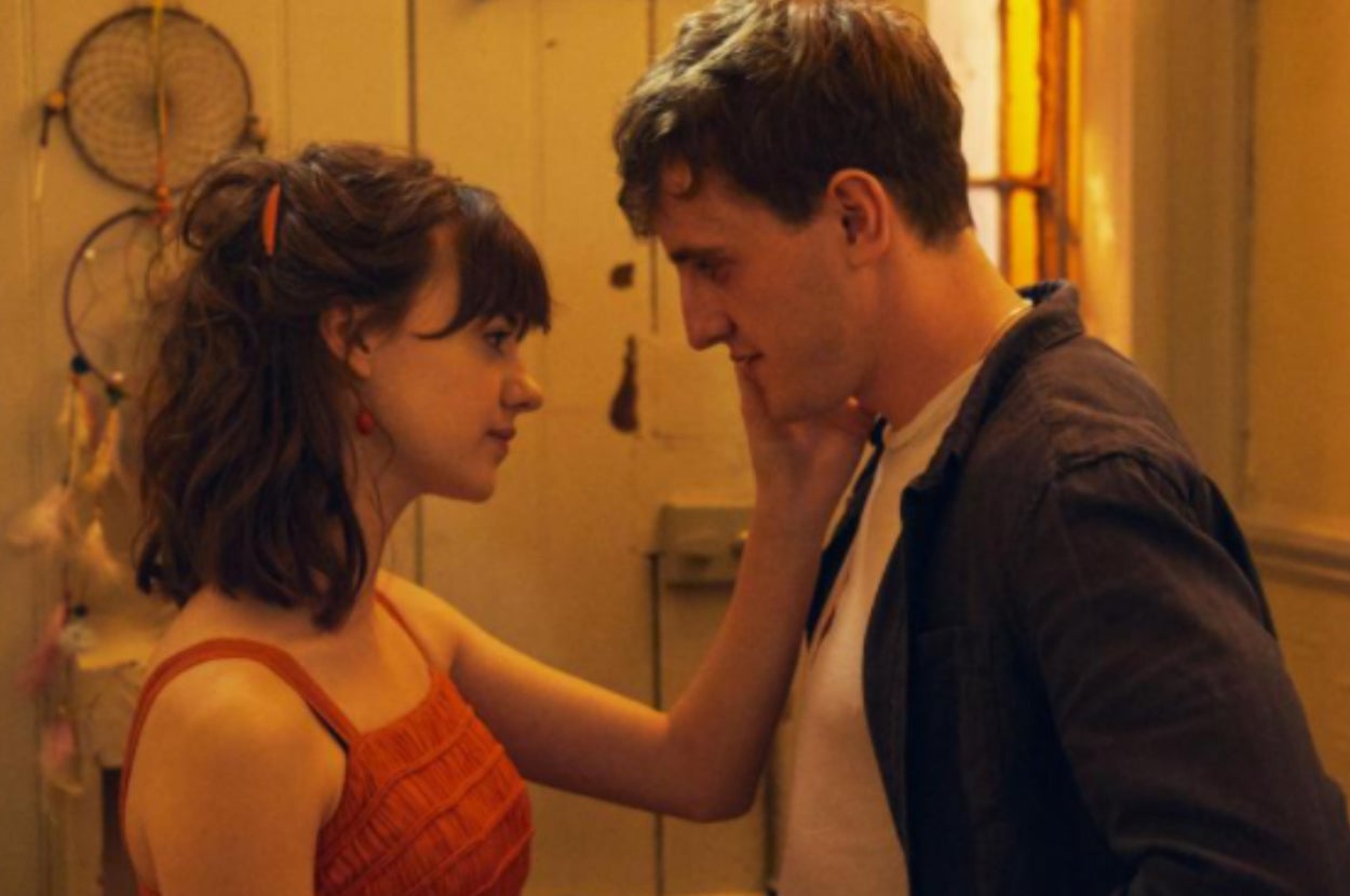 Marianne holds her hand up to Connell face as he gazes down at her.