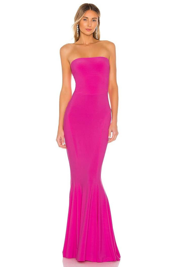 Model wearing hot pink gown that is tight and flares past the knee