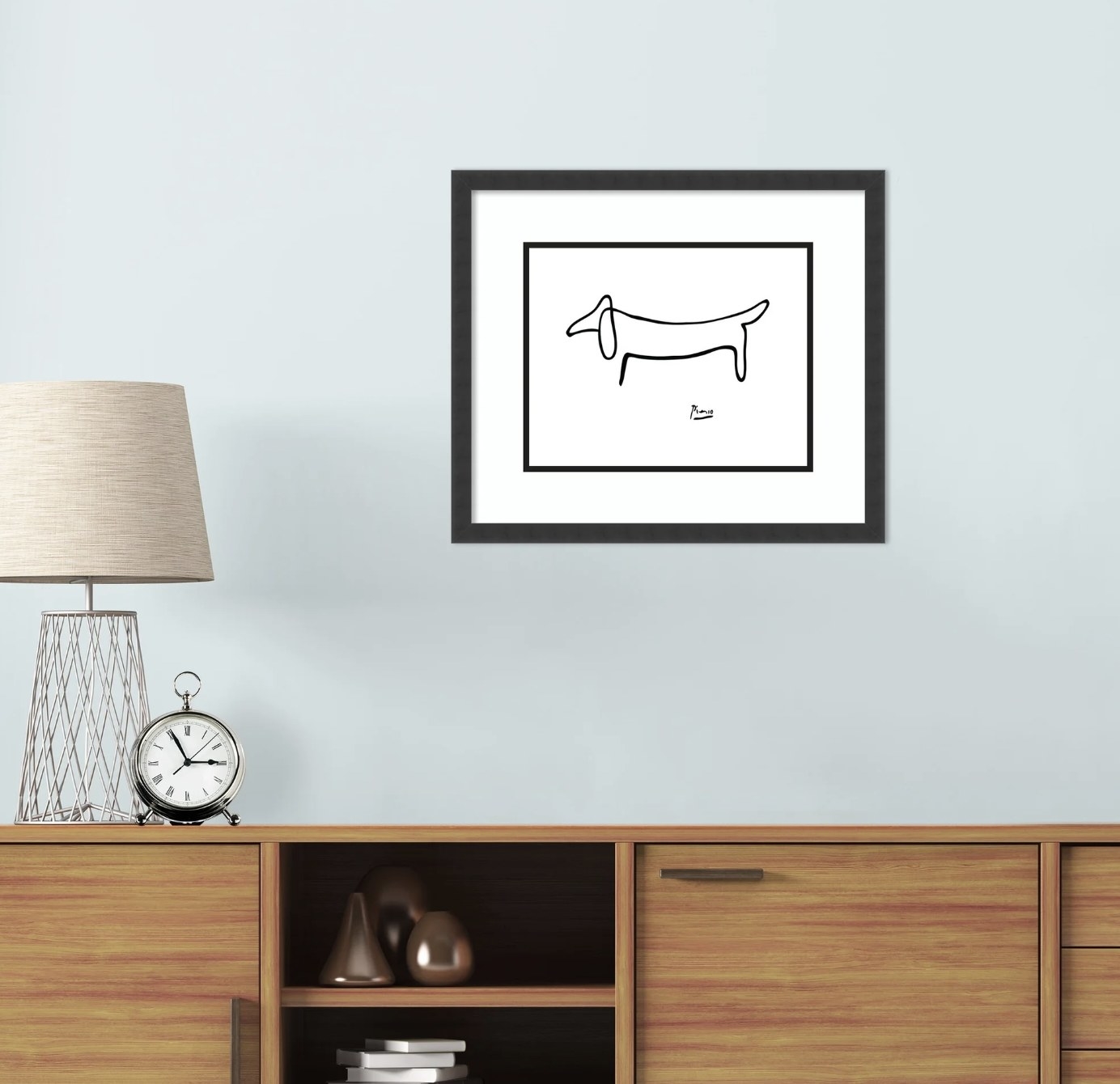 A framed Pablo Picasso print hanging above a console table