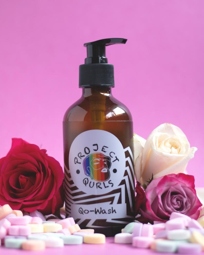 image of the the qo-wash against a bright pink background, surrounded by roses and sweetheart candies