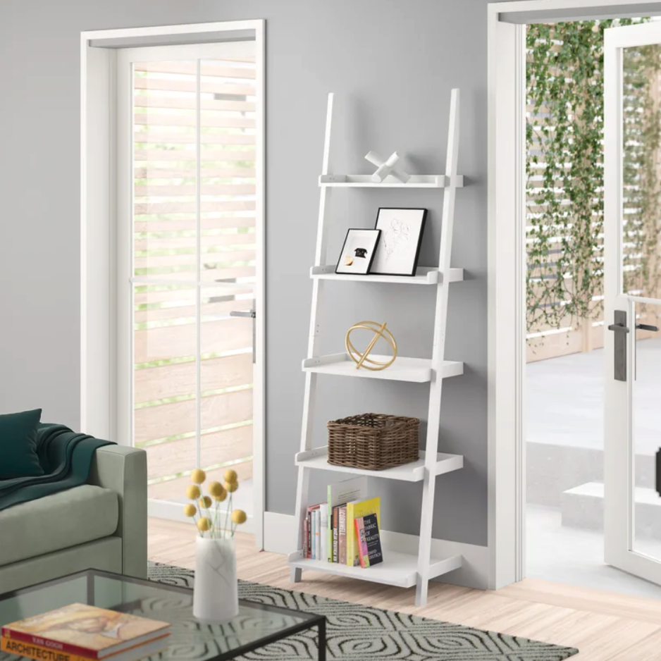 white ladder bookcase leaning against a wall with decor on the shelves