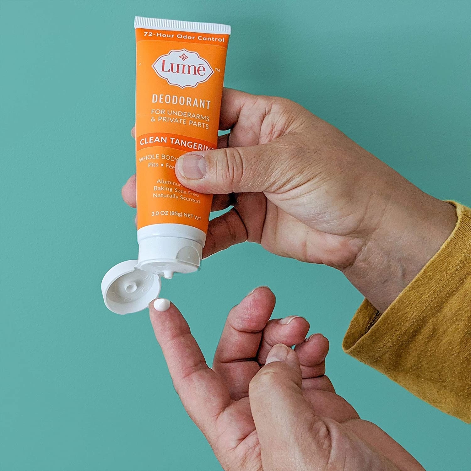 Model squeezing Lume deodorant cream onto fingertip