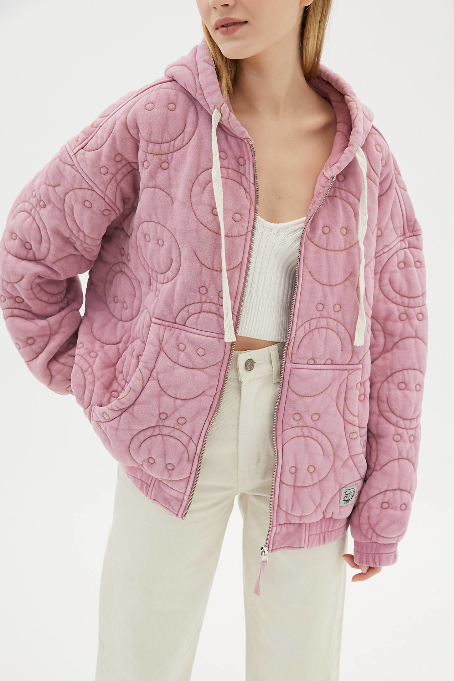 A model wearing the jacket in pink with quilted smiley faces