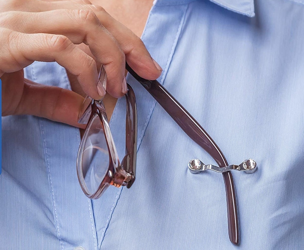 A pair of glasses hanging from a clip attached to a person&#x27;s button up shirt