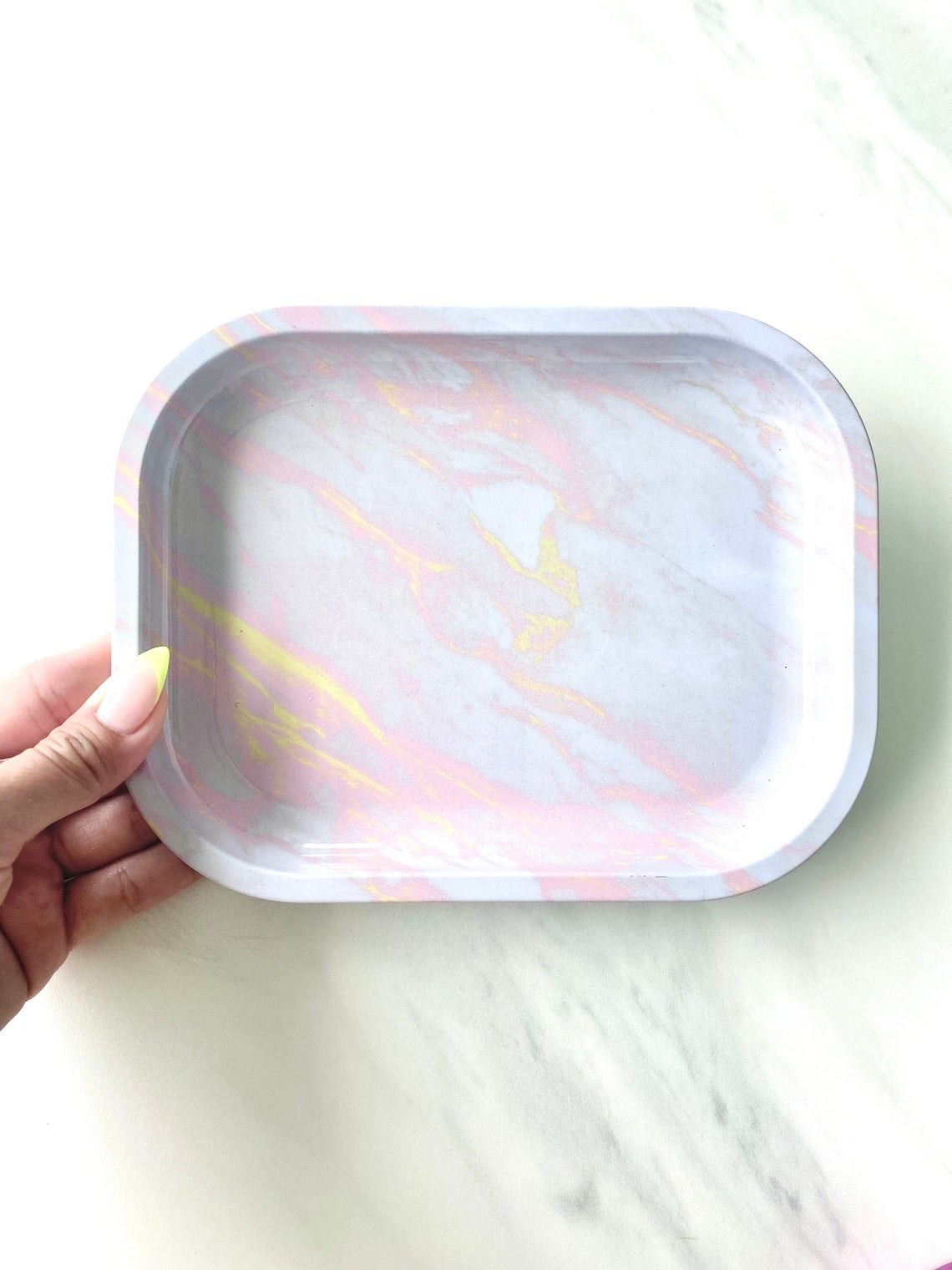 the marble rolling tray in pink and yellow marble streaks on an opal dish