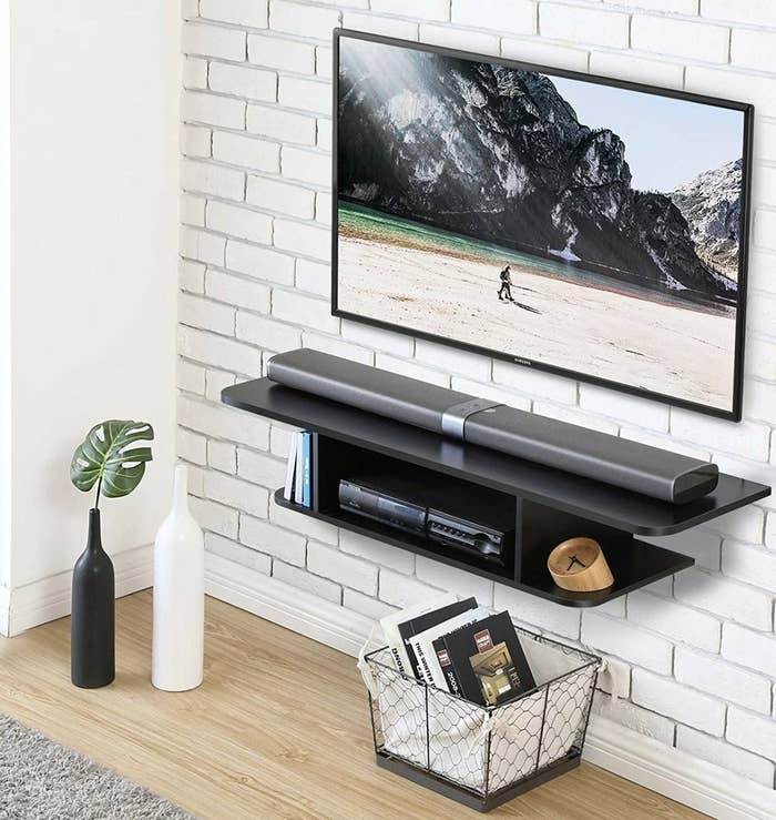 A black floating TV stand mounted on a wall