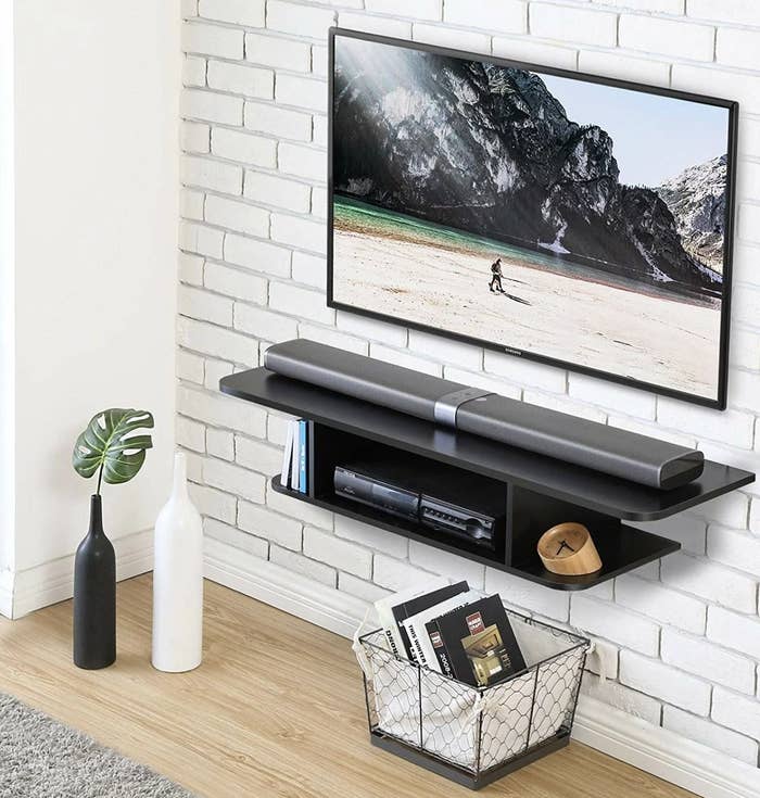 A black floating TV stand mounted on a wall
