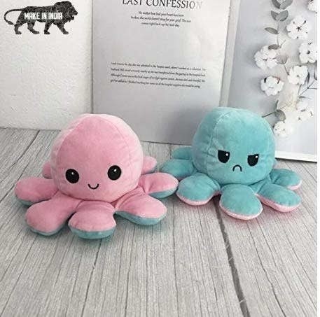 The octopus plushie is pink with a smiley face on one side and blue with a frown on the other.