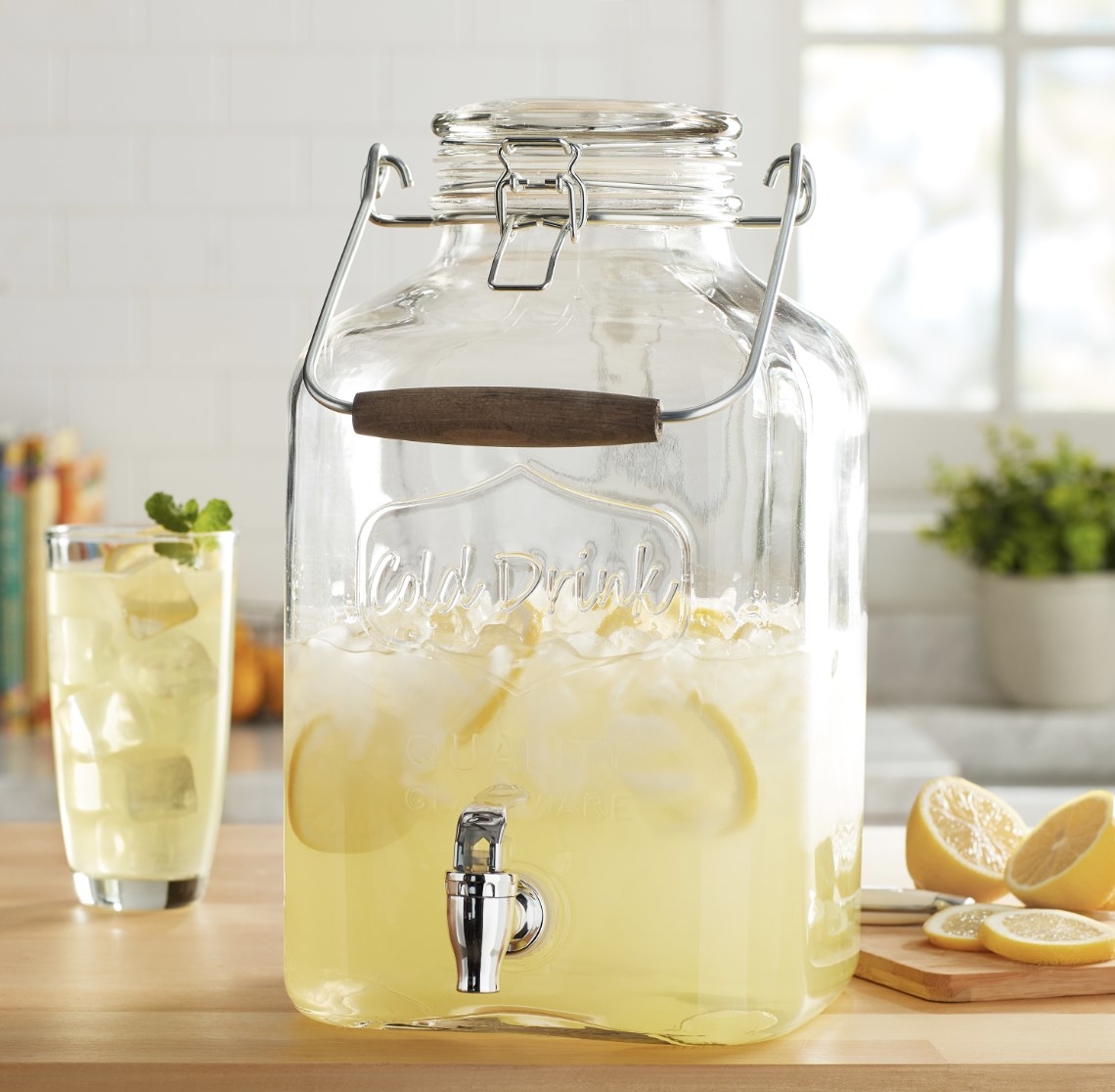 The glass container is filled halfway with lemonade, ice and lemon slices