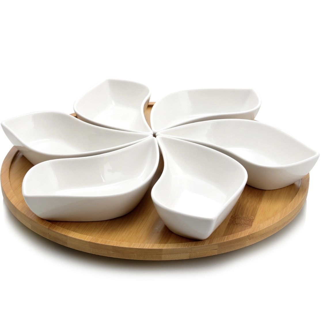 The white stoneware is shaped in a flower and there is a tan rotating tray underneath