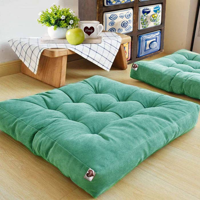 Two green floor cushions in a bedroom.