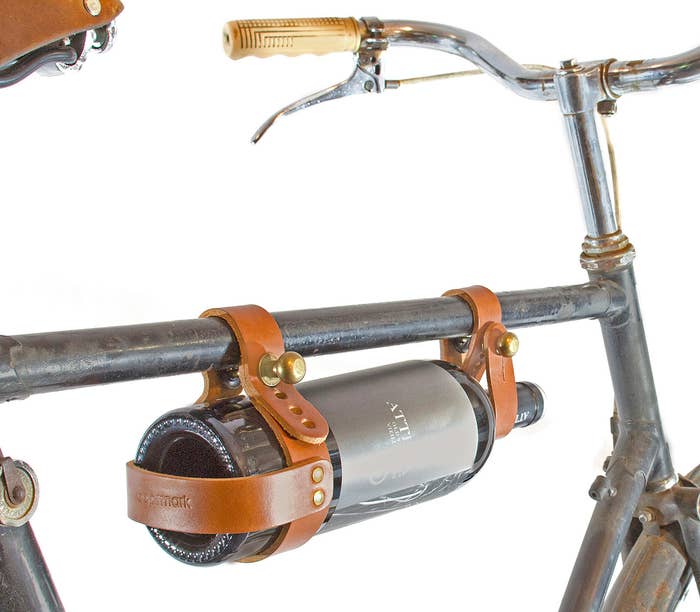 A wine bottle carried on a bike by two leather straps 
