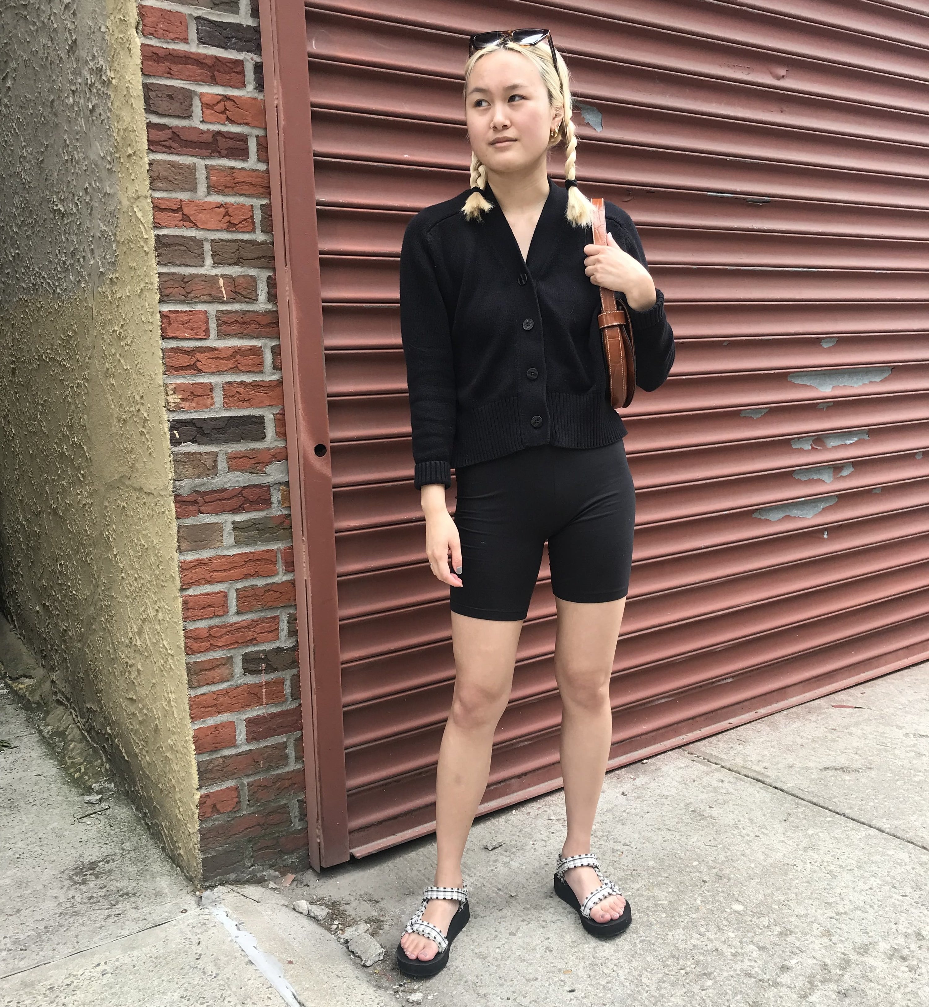 BuzzFeed Editor wearing the sandals with black bike shorts and a black cardigan