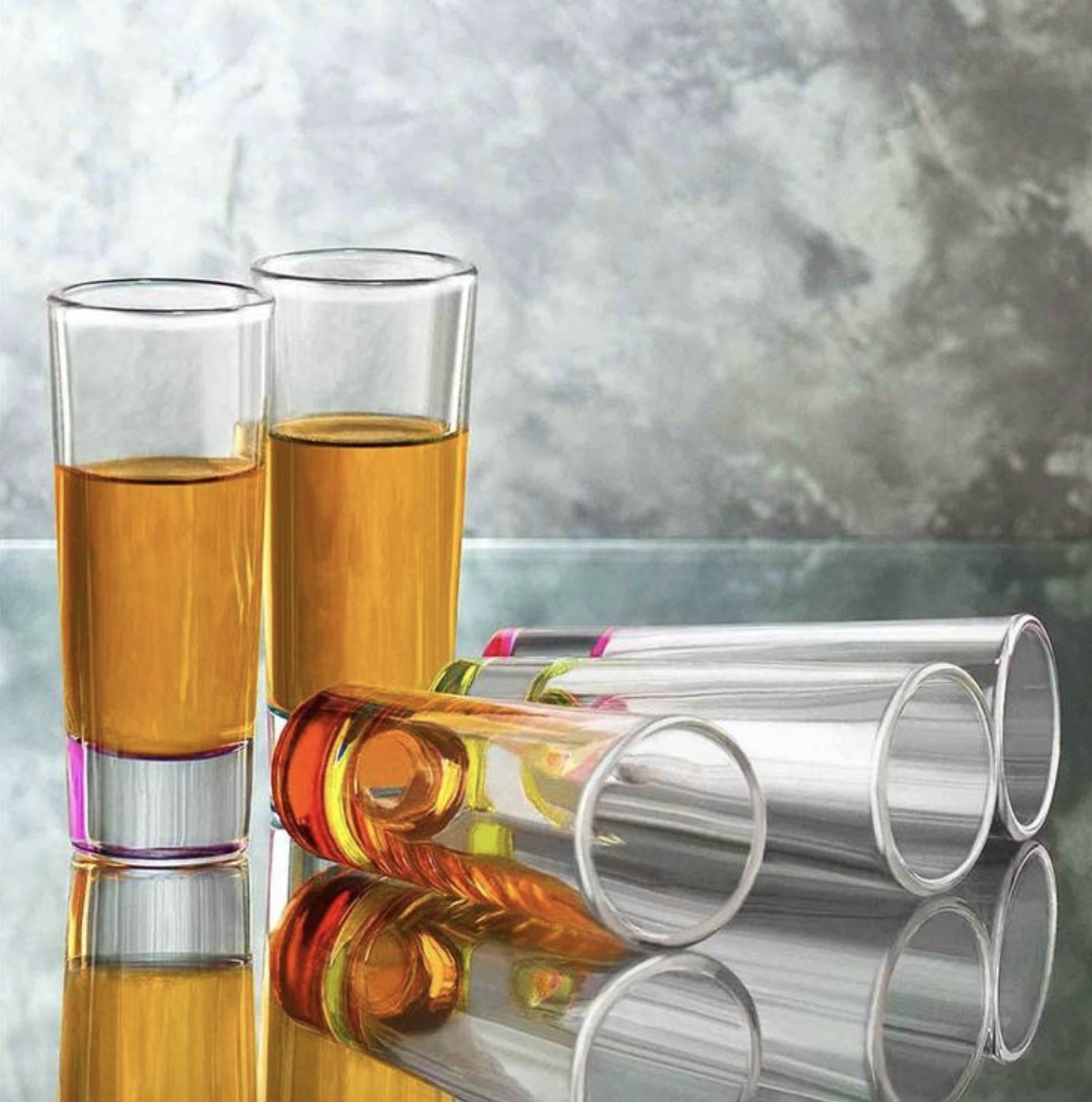 There are two glasses filled with an amber liquid and three others laying horizontally nearby