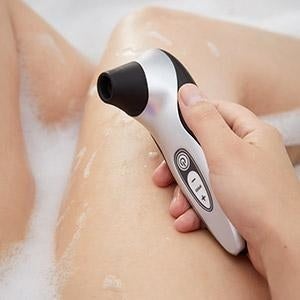 Model holding silver and black suction vibrator in bathtub