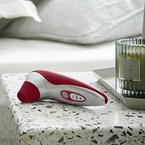 Red and silver suction vibrator sitting on nightstand
