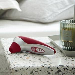 Red and silver suction vibrator sitting on nightstand