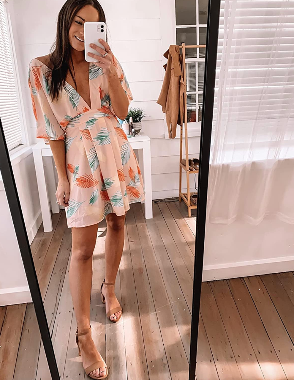 reviewer wearing the blush tone dress with a teal and orange feather all over pattern