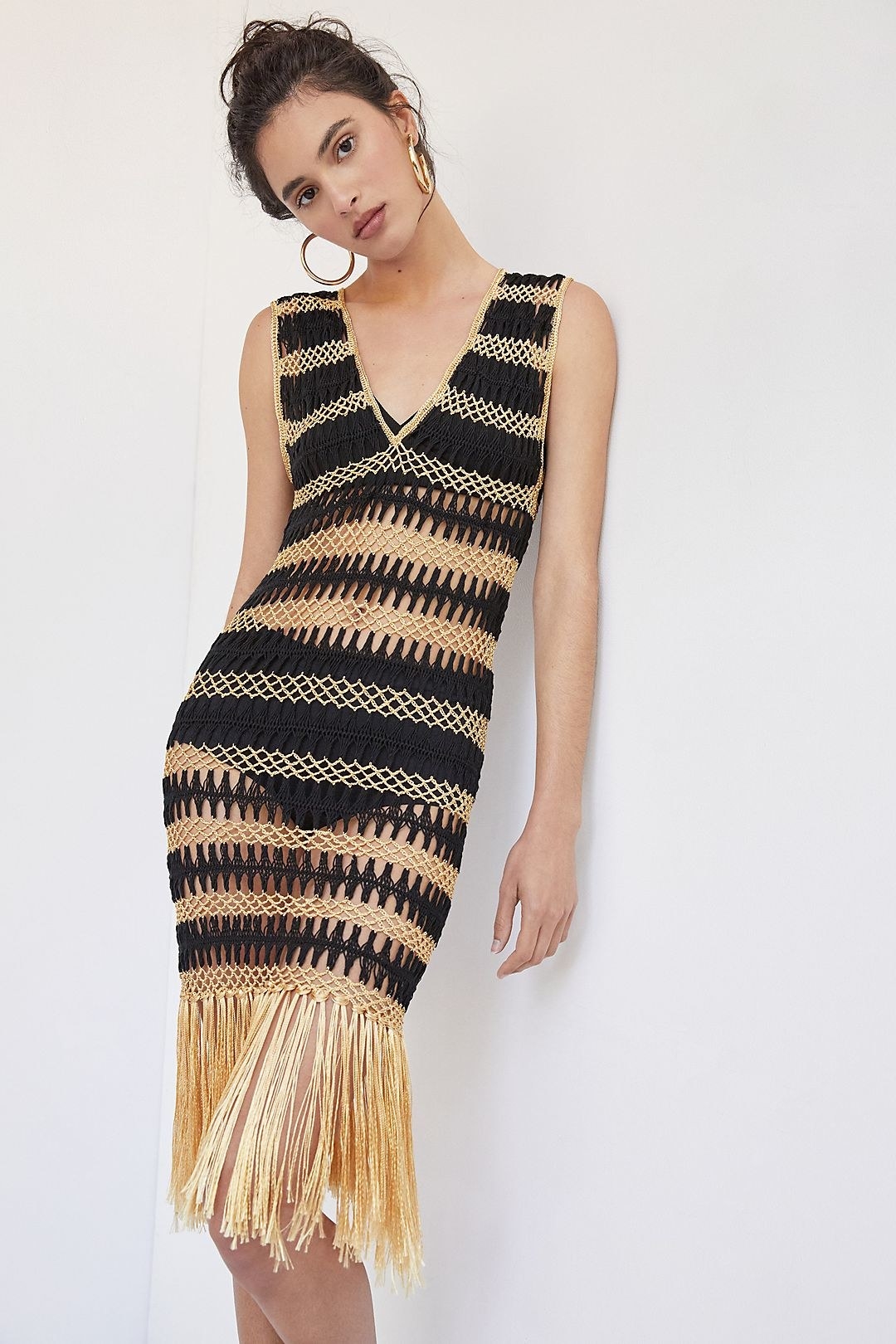 a model wears the fringed crochet cover up over a black bikini