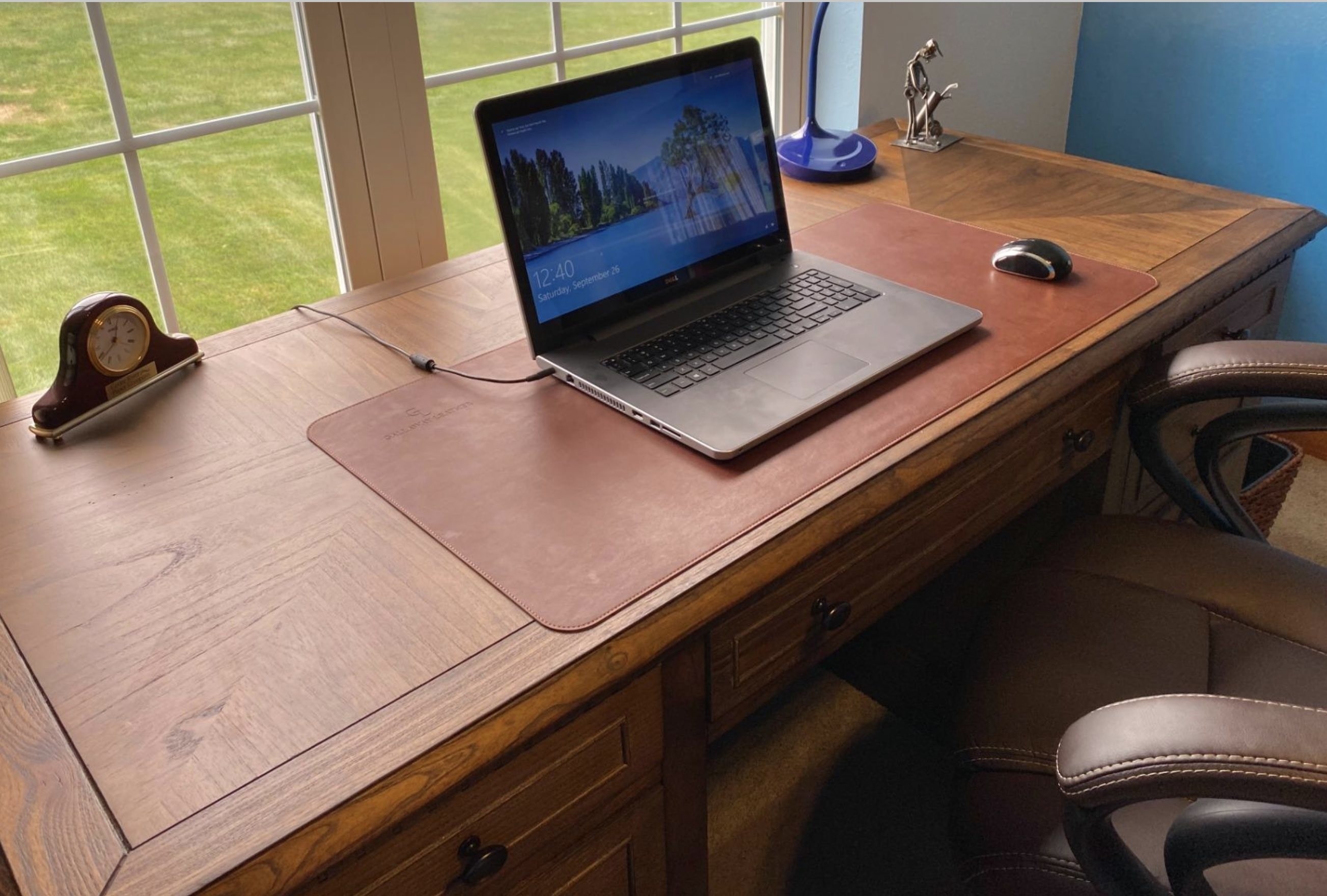 a brown leather desk pad on top of a wide wooden desk