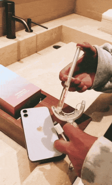 GIf of person filling their trays with whitening gel and plugging it into their phone to turn on the whitening light