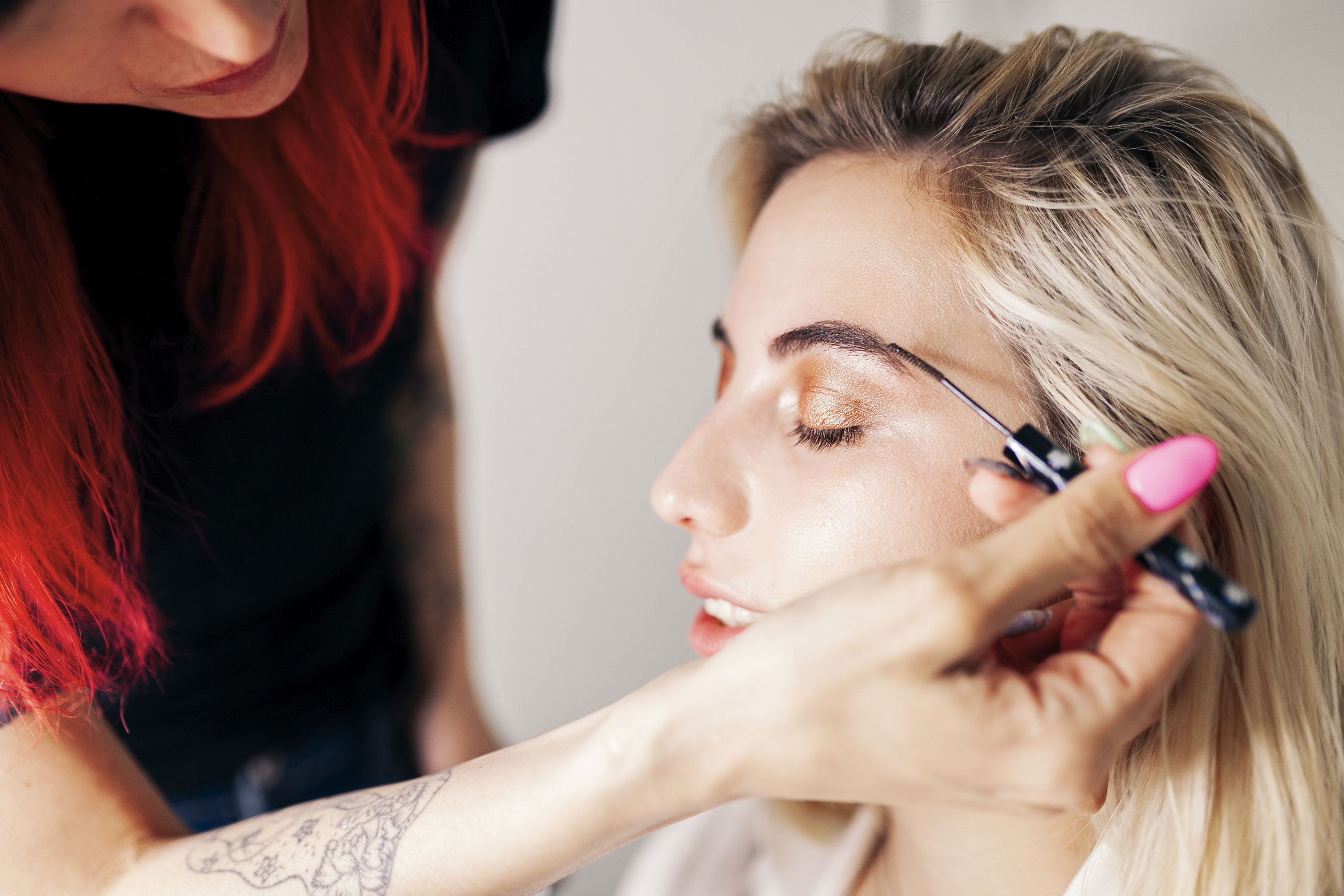 A person getting their eyebrows done by a makeup artist