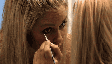 A person adding eyeliner to their bottom lid
