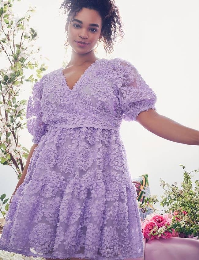 model wearing purple dress with bow tie in back and poofy sleeves
