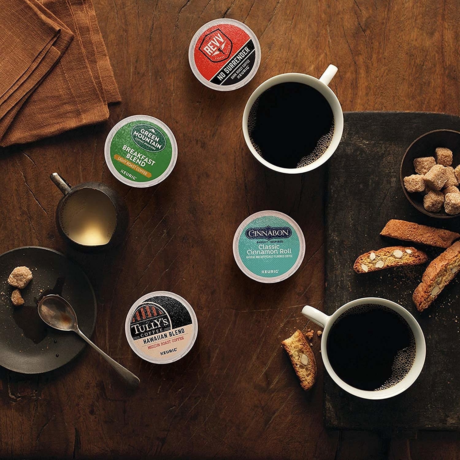 Four K-Cup pods on a table with two cups of coffee