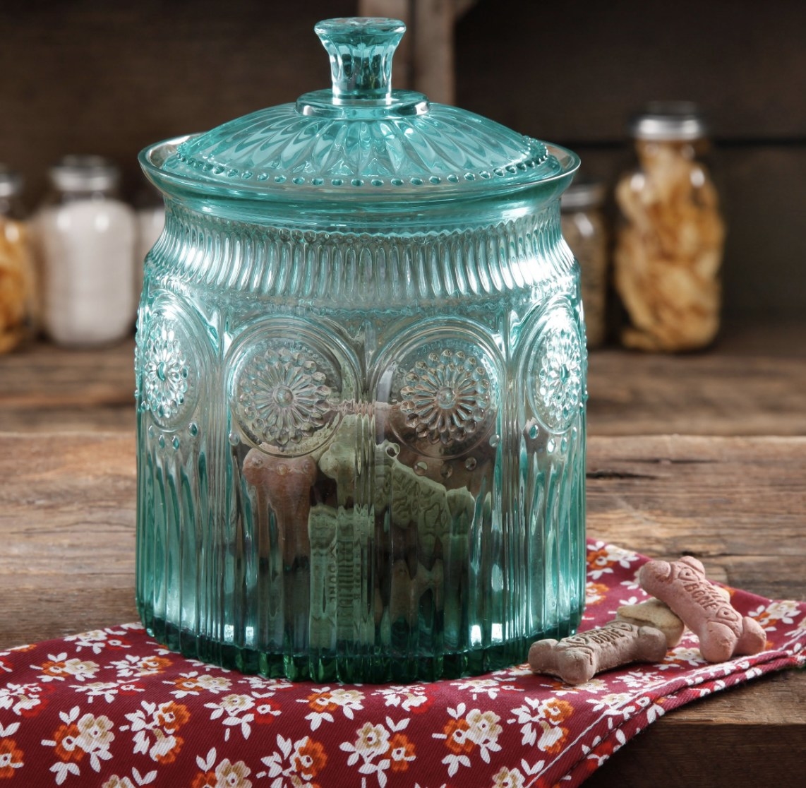 The blue glass jar has ornate detailing and is full of pet treats